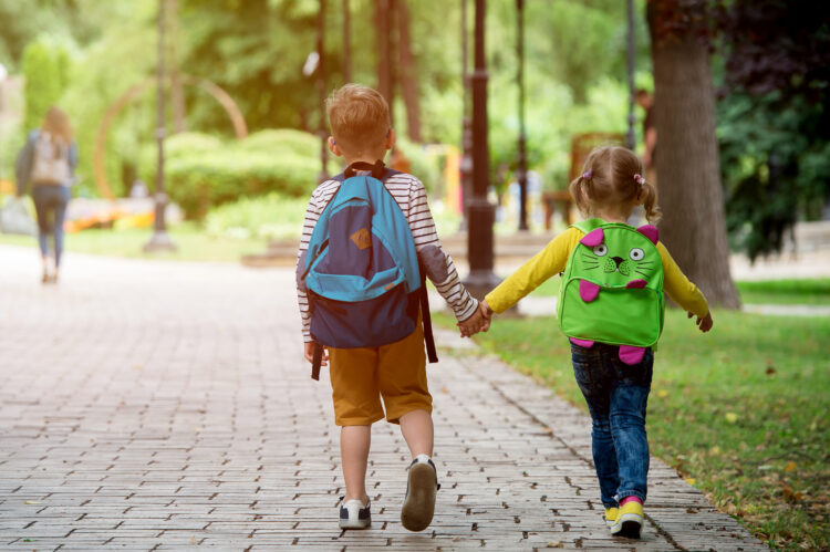 Kaksi lasta reput selässä matkalla kouluun.